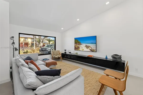a living room with furniture floor to ceiling window and a flat screen tv