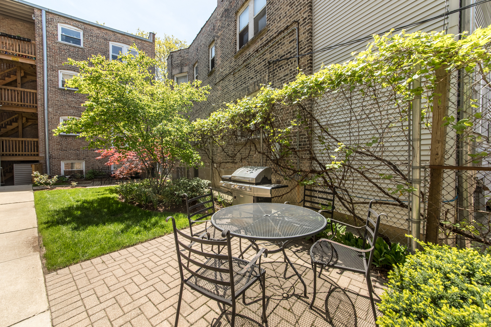4306 North Clark Street, Unit 2 Chicago, IL 60613 - Photo 22 of 25 a backyard of a house with table and chairs plants and large tree