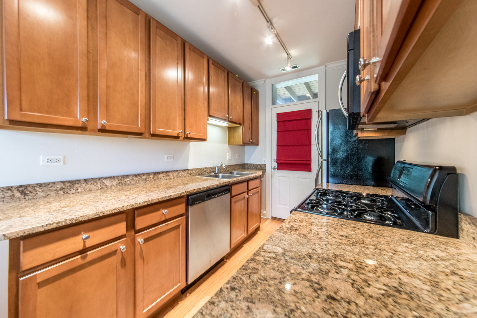 4306 North Clark Street, Unit 2 Chicago, IL 60613 - Photo 9 of 25 a kitchen with stainless steel appliances granite countertop a stove a sink dishwasher and cabinets with wooden floor