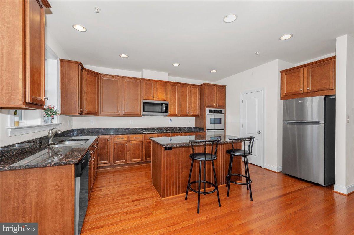 741 Appalachian Way Brunswick, MD 21716 - Photo 9 of 44 a kitchen with stainless steel appliances granite countertop wooden floor a refrigerator a sink a stove a dining table and chairs