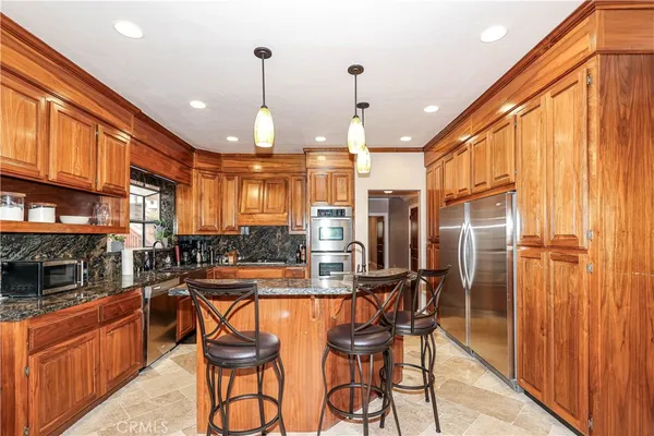 a kitchen with stainless steel appliances granite countertop a stove a sink and a refrigerator