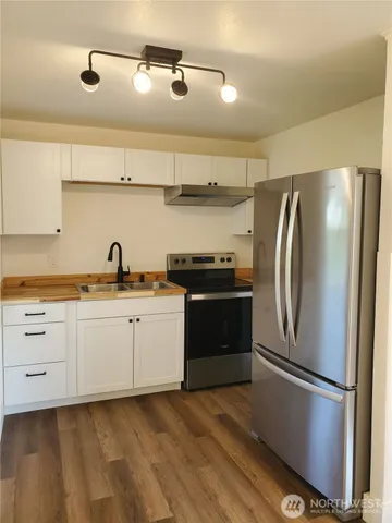 a kitchen with cabinets stainless steel appliances and wooden floor