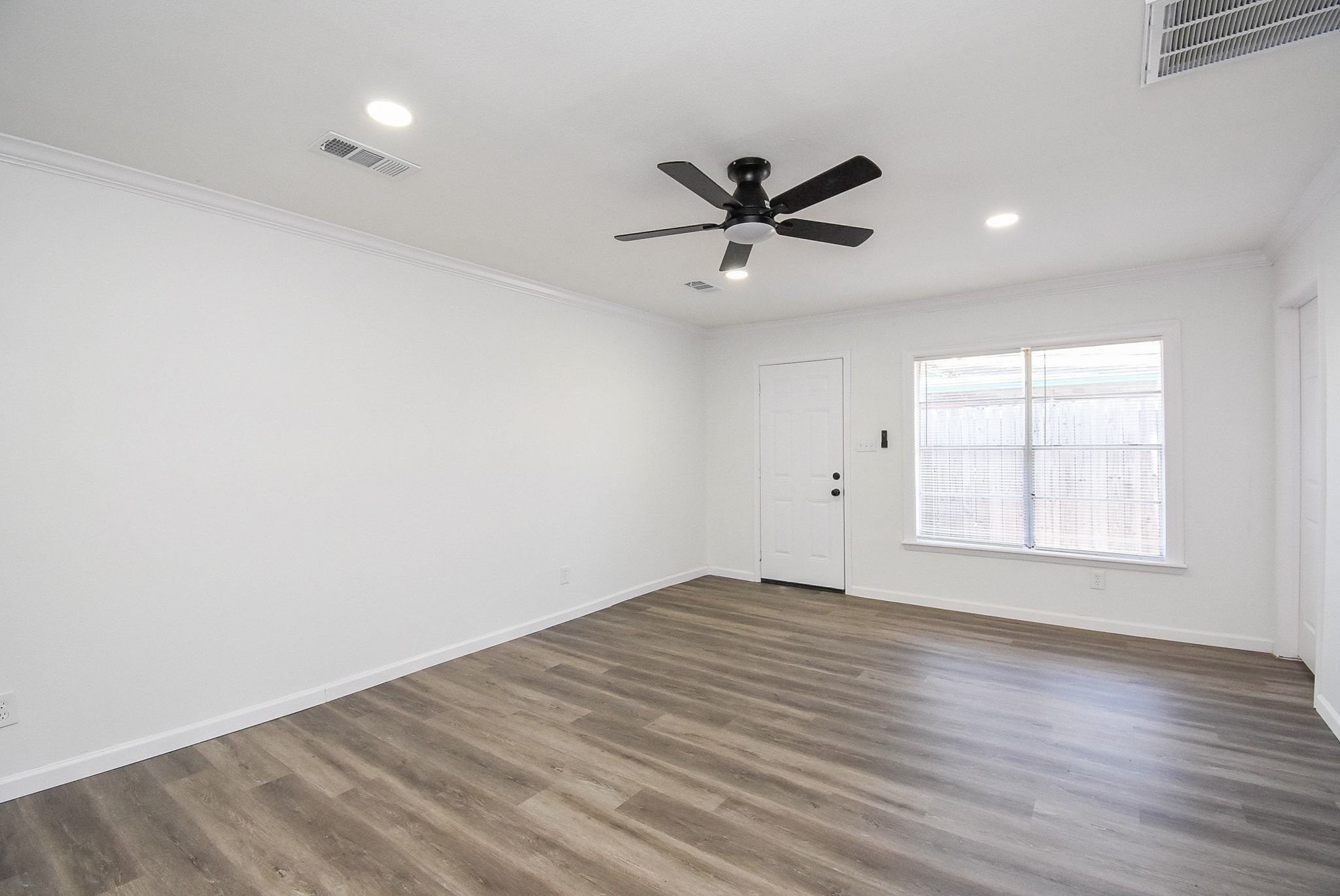 514 Peach Spring Drive Houston, TX 77037 - Photo 13 of 27 an empty room with wooden floor fan and windows