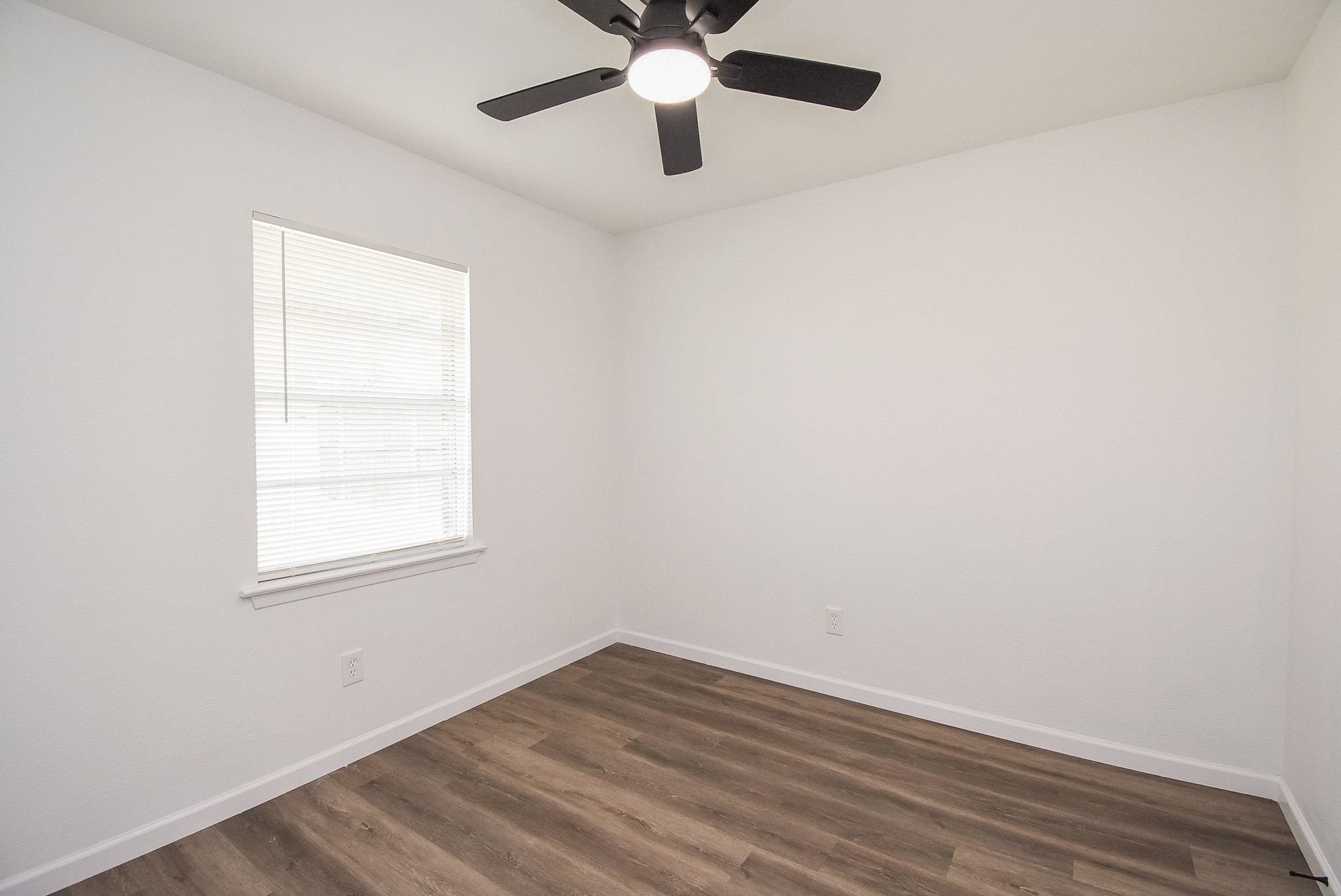 514 Peach Spring Drive Houston, TX 77037 - Photo 24 of 27 an empty room with wooden floor chandelier fan and windows