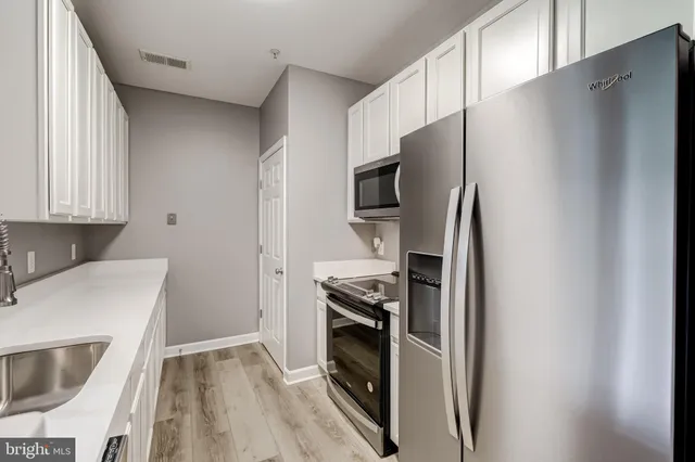 a kitchen with stainless steel appliances a refrigerator a sink a stove top oven a refrigerator and dishwasher