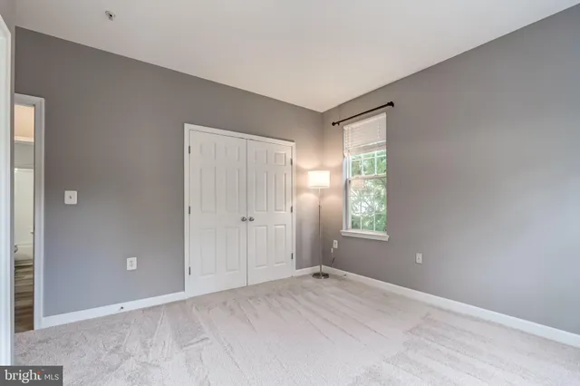 a view of an empty room with window and closet area
