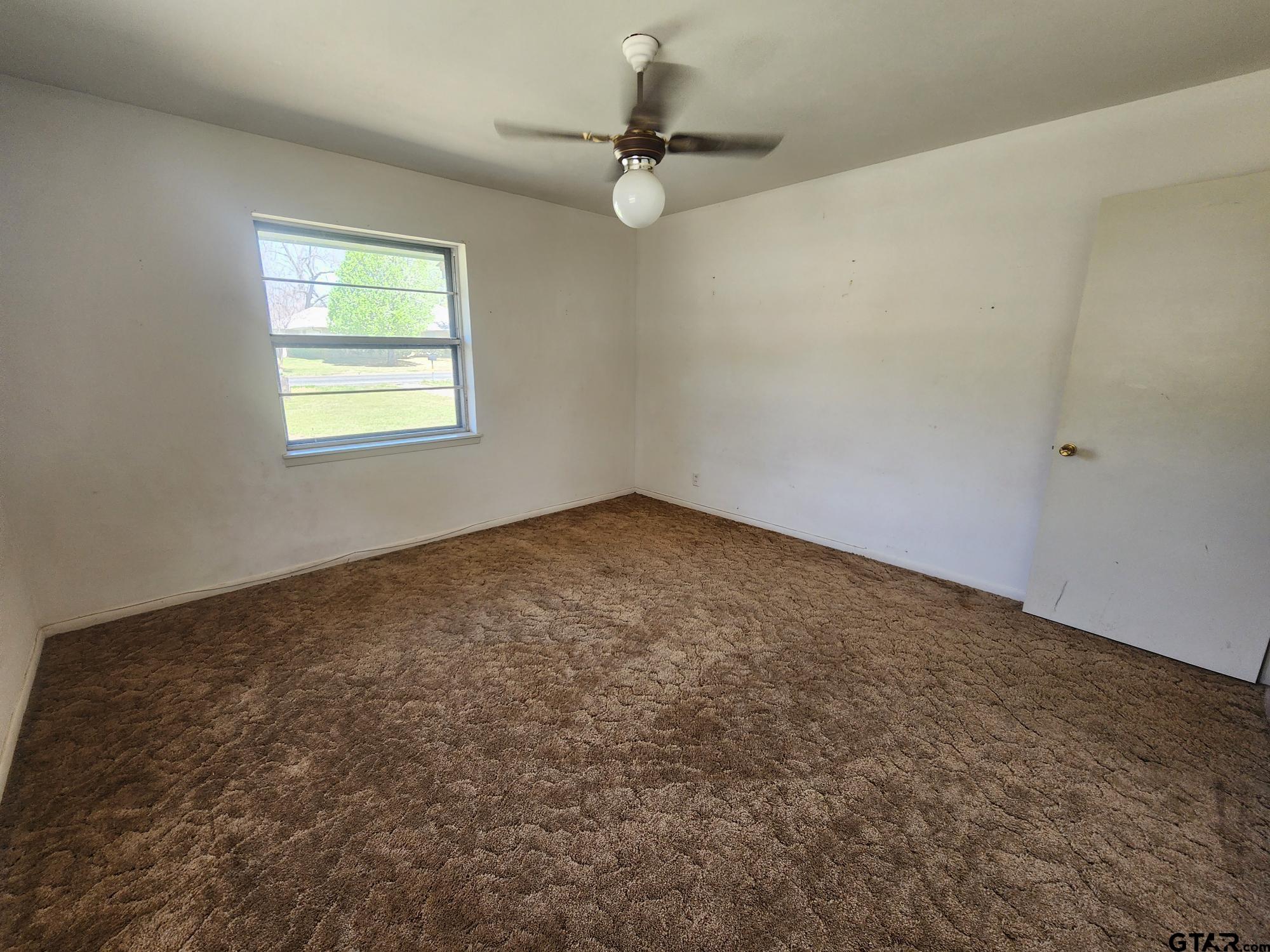 512 E Lane Quitman, TX 75783 - Photo 28 of 32 an empty room with a window and a fan