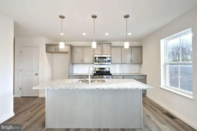 a kitchen with kitchen island granite countertop a sink a counter space appliances and cabinets