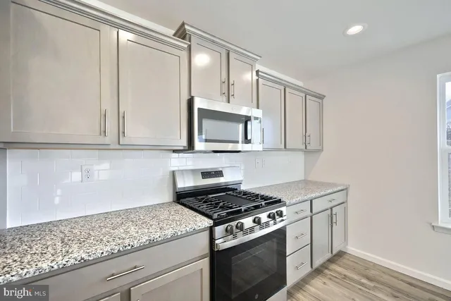 a kitchen with granite countertop cabinets stainless steel appliances and wooden floor