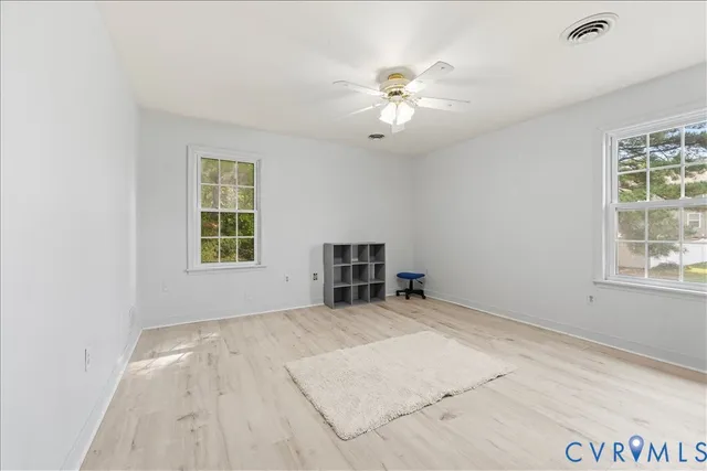 an empty room with windows and fan