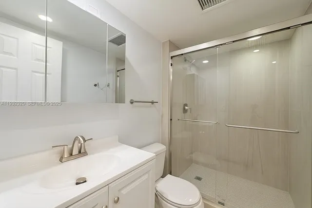 a bathroom with a sink mirror shower and toilet