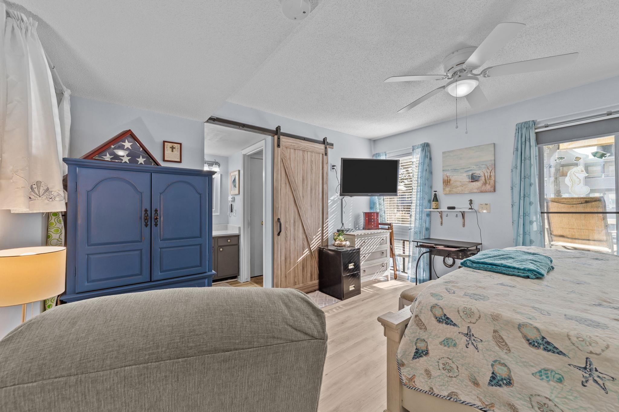 351 Lake Arrowhead Road, Unit 211 Myrtle Beach, SC 29572 - Photo 14 of 40 Bedroom featuring a barn door, ensuite bathroom, a textured ceiling, ceiling fan, and light wood-style floors