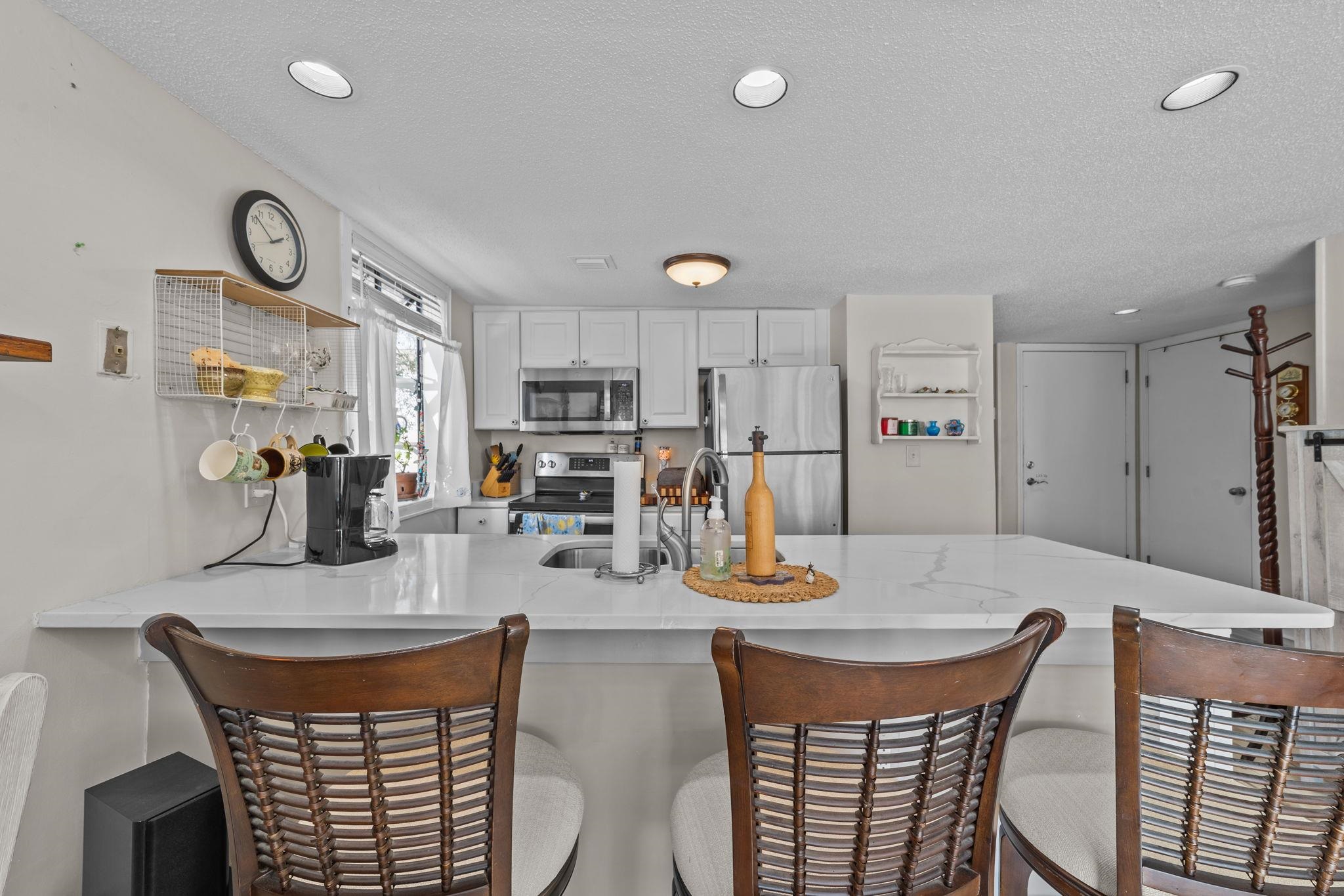 351 Lake Arrowhead Road, Unit 211 Myrtle Beach, SC 29572 - Photo 8 of 40 Kitchen featuring a peninsula, a breakfast bar, stainless steel appliances, white cabinetry, and a textured ceiling