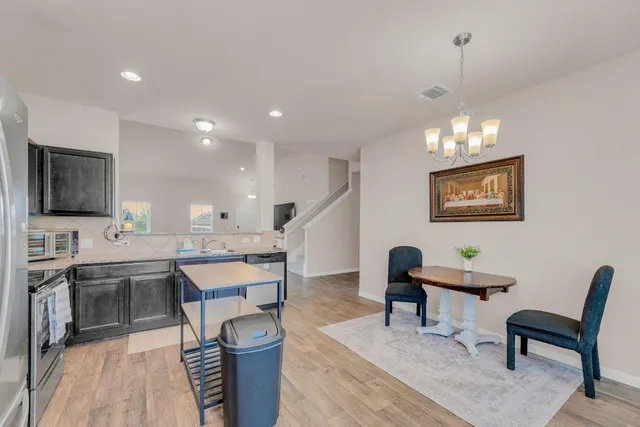 a living room with stainless steel appliances kitchen island granite countertop furniture a rug and a chandelier