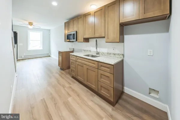 a kitchen with a sink a stove cabinets and wooden floor