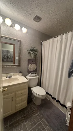 a bathroom with a granite countertop sink toilet and mirror