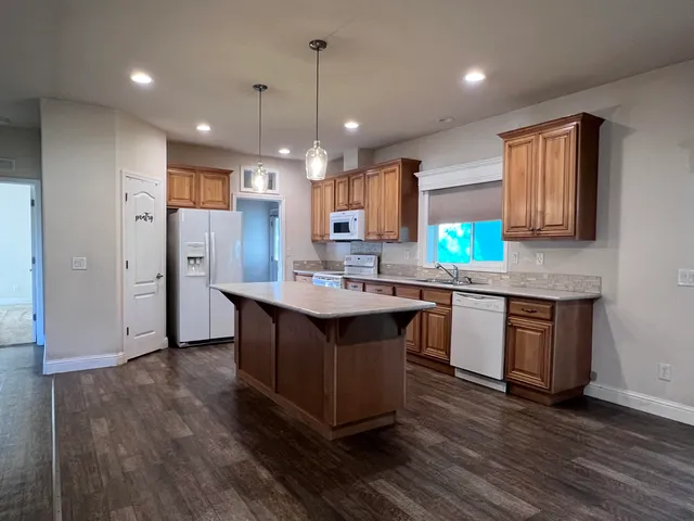 a kitchen with kitchen island granite countertop wooden floors and white cabinets