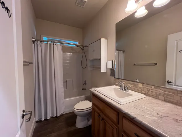 a bathroom with a granite countertop sink toilet and shower
