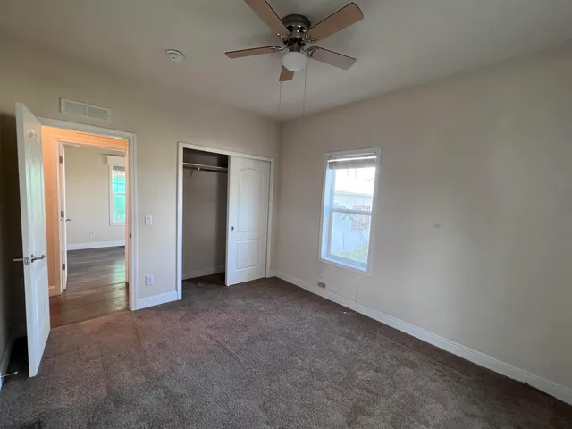 an empty room with windows and fan