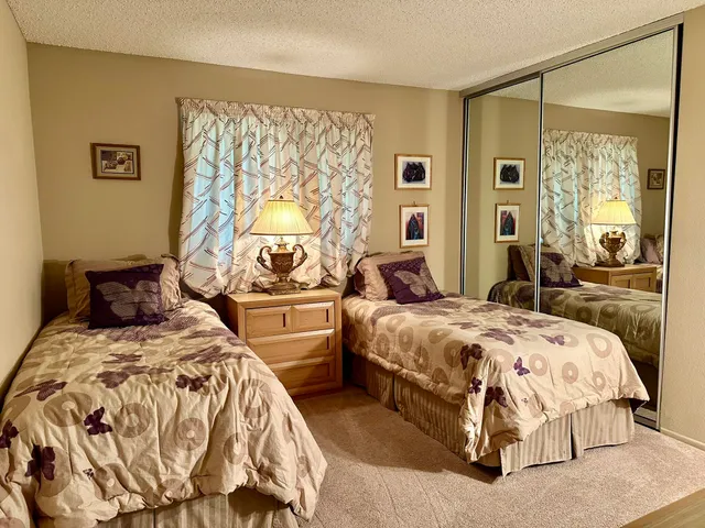 a bedroom with two beds and a large mirror next to a window
