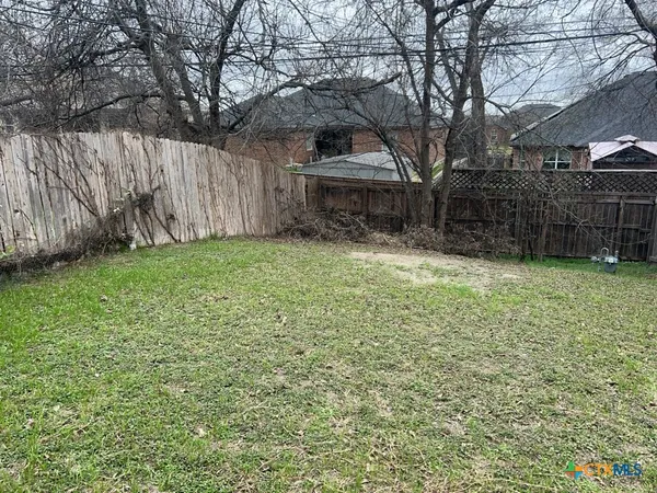 a view of a backyard with wooden fence and a large tree