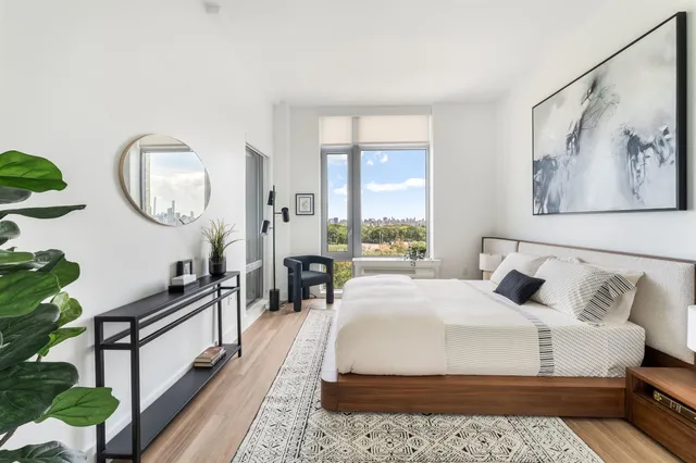a bedroom with a bed a mirror and a large window with the garden view