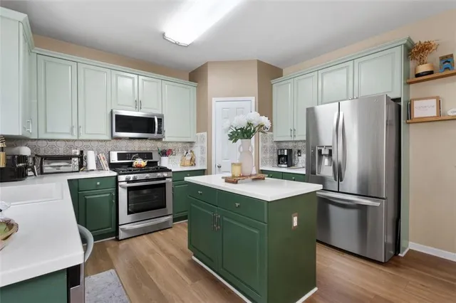 a open kitchen with stainless steel appliances granite countertop a sink dishwasher a stove and a refrigerator with wooden floor