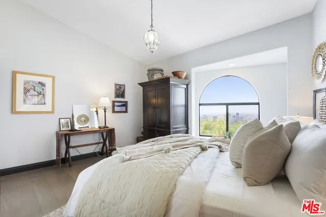 a spacious bedroom with a bed a chandelier and a dresser
