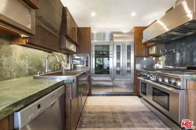 a kitchen with stainless steel appliances granite countertop a stove a sink and a refrigerator