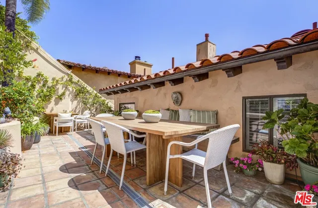 a patio with table and chairs and potted plants