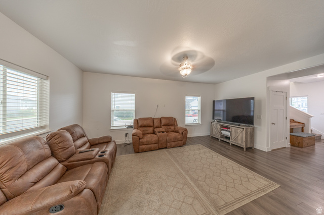 4765 Breezy Patch Road Eagle Mountain, UT 84005 - Photo 7 of 25 Spacious living area featuring wood-finish flooring, a neutral tone area rug, and ample natural light from multiple windows