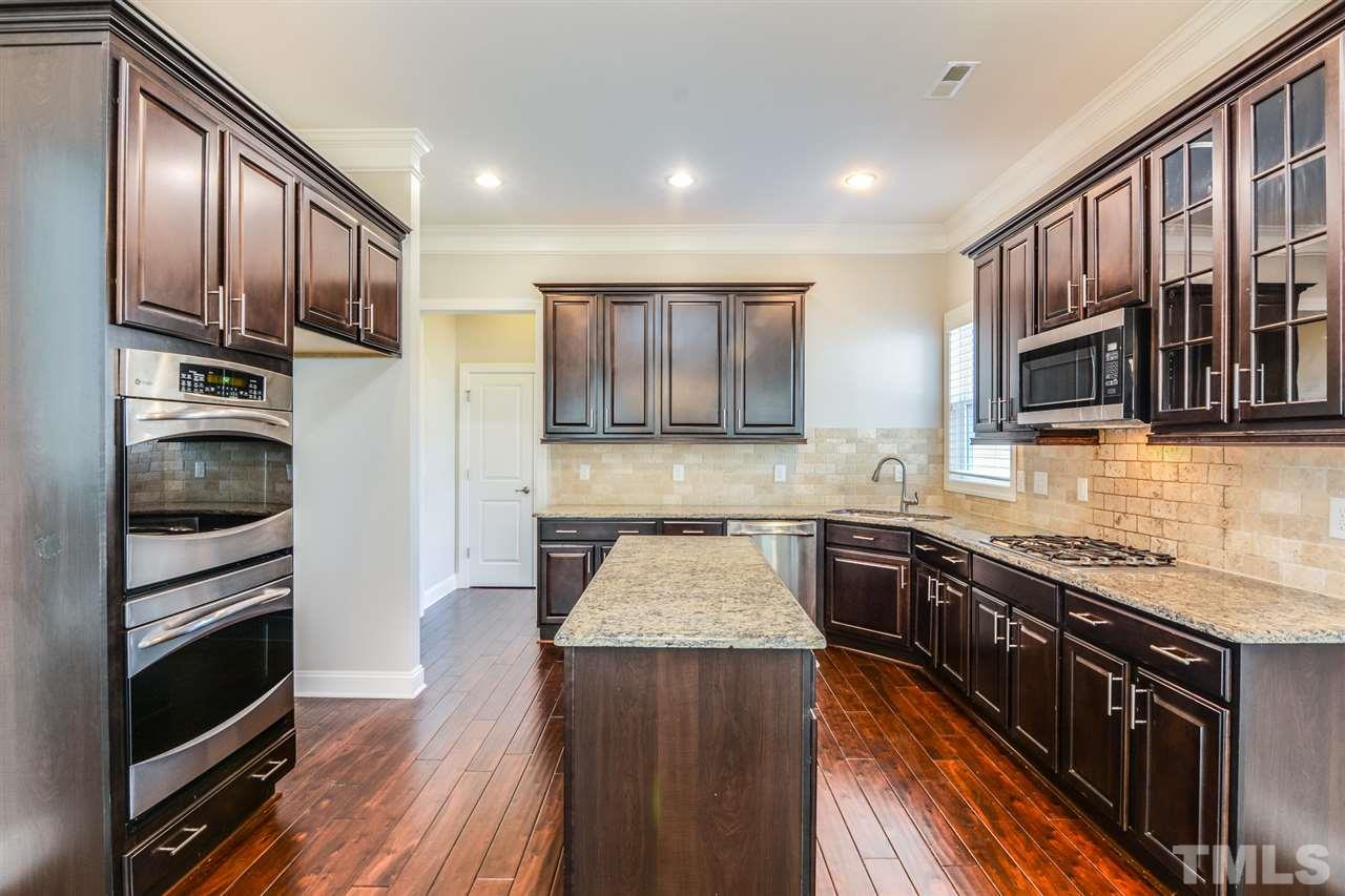 5646 Wade Park Boulevard Raleigh, NC 27607 - Photo 2 of 20 a kitchen with stainless steel appliances granite countertop wooden cabinets a stove top oven a sink and dishwasher a oven with wooden floor