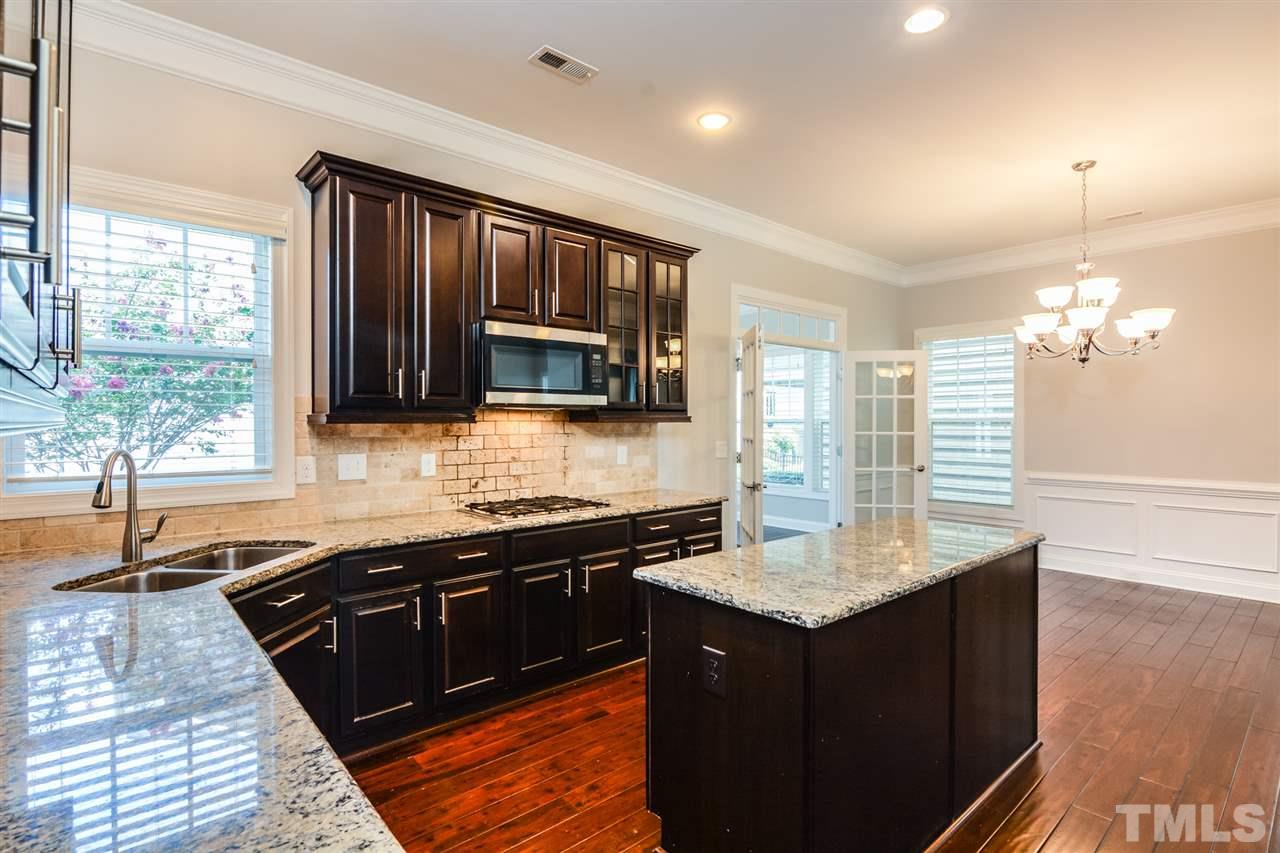5646 Wade Park Boulevard Raleigh, NC 27607 - Photo 4 of 20 a kitchen with granite countertop a sink dishwasher stove and cabinets with wooden floor