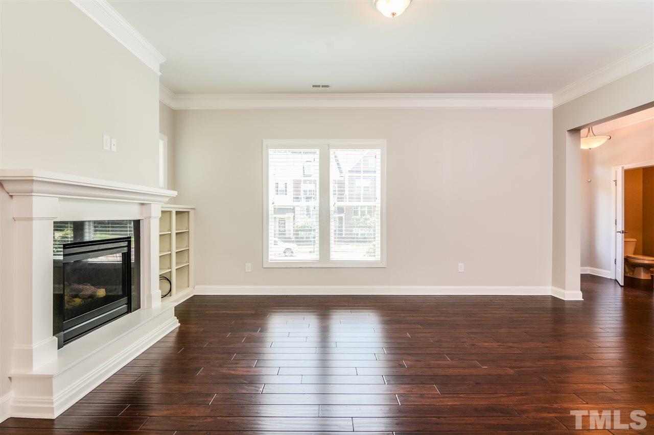 5646 Wade Park Boulevard Raleigh, NC 27607 - Photo 6 of 20 a view of an empty room with wooden floor fireplace and a window