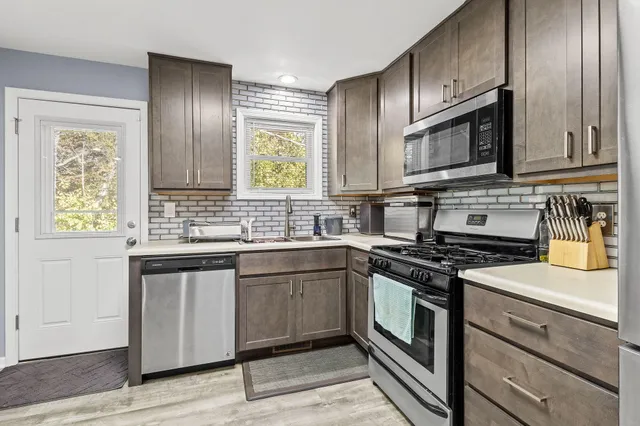 a kitchen with stainless steel appliances granite countertop a stove a sink and a microwave