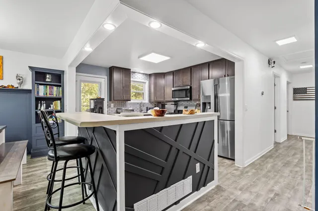 a kitchen with kitchen island granite countertop wooden floors cabinets and stainless steel appliances