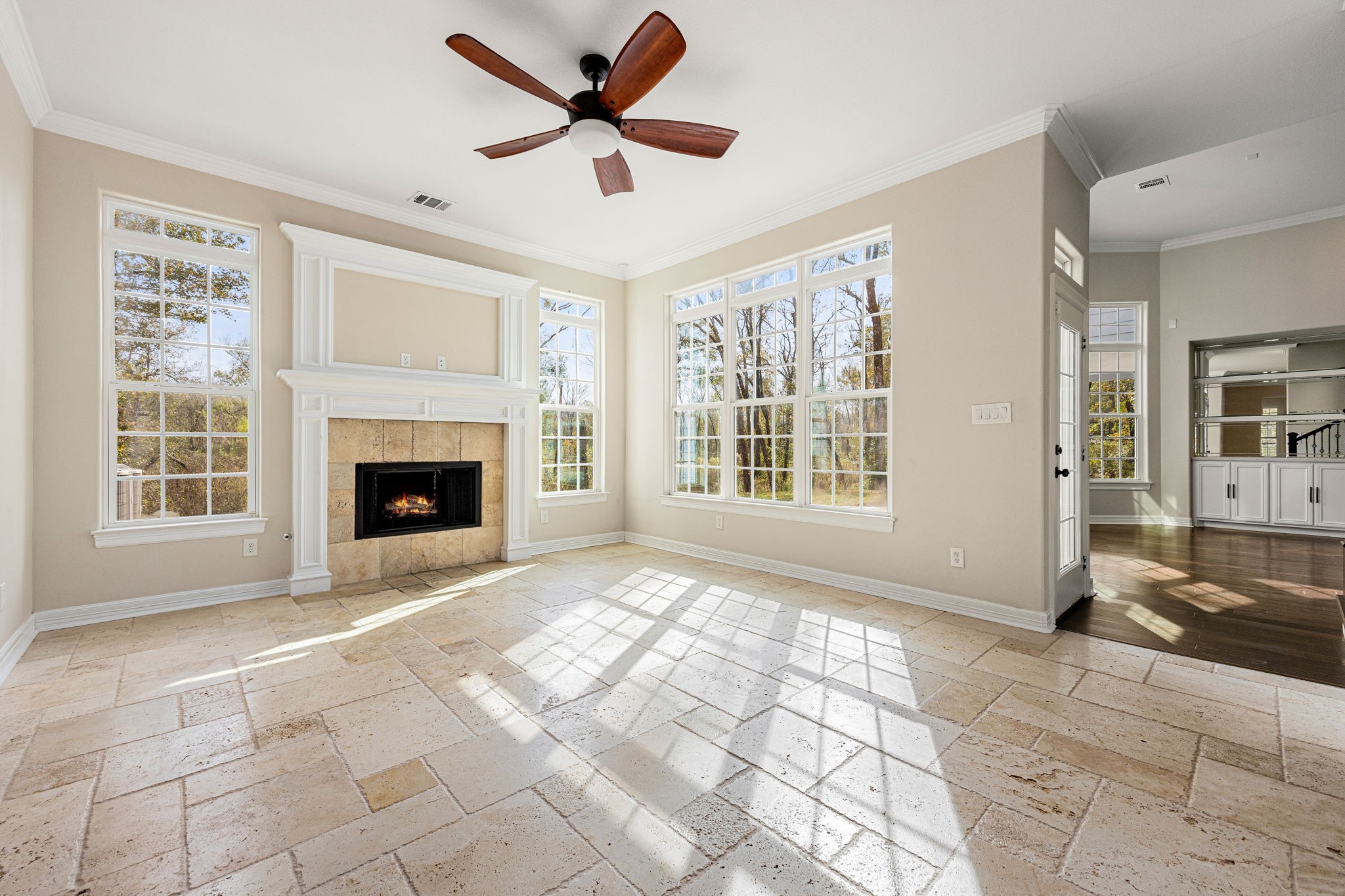 14882 Gingham Road Montgomery, TX 77356 - Photo 12 of 41 Bright family room with large windows, a ceiling fan, and a cozy fireplace. The space features light tiled flooring, high ceilings, and an open layout leading to other areas of the home.