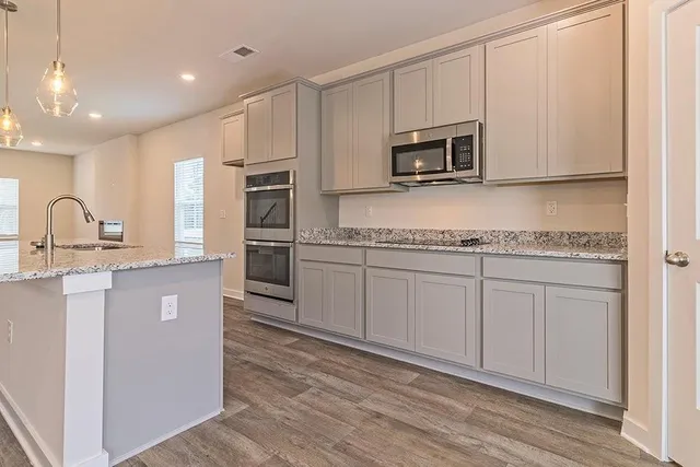 a kitchen with stainless steel appliances granite countertop a stove a sink and a microwave