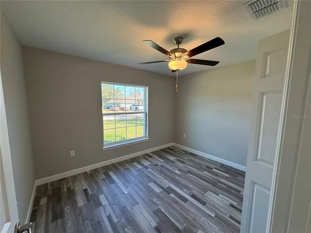 a view of an empty room with a window and wooden floor