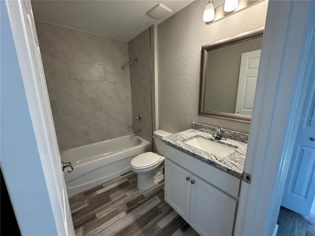 a bathroom with a granite countertop toilet sink and mirror