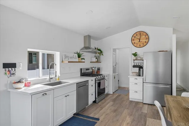 a kitchen with a refrigerator a stove a sink and a dining table with wooden floor