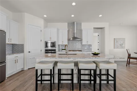 a kitchen with stainless steel appliances granite countertop a dining table chairs and white cabinets