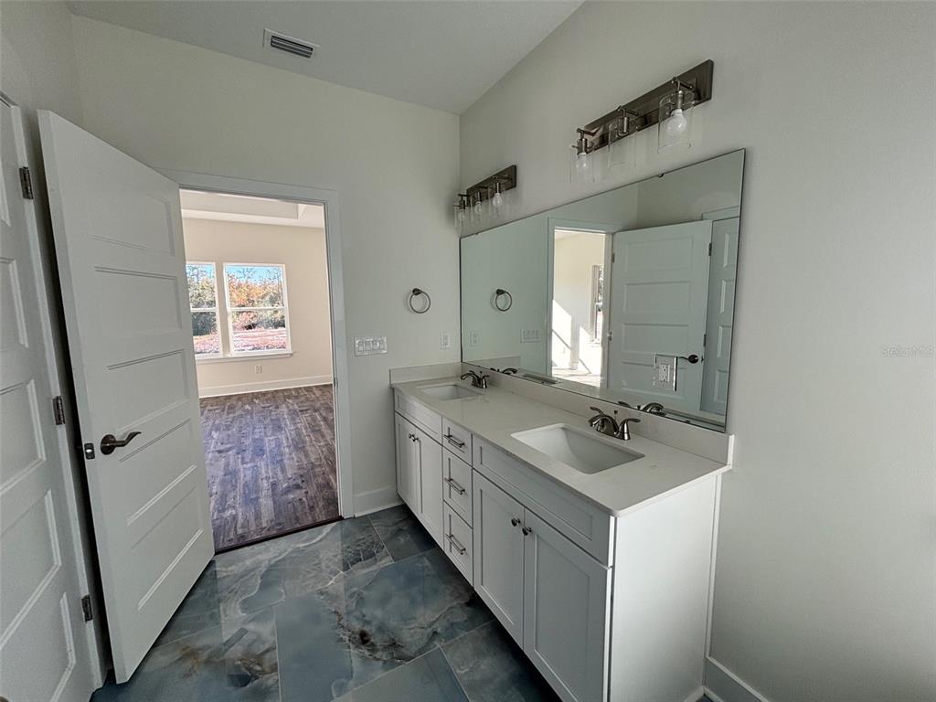 5949 South E County Road 21B Keystone Heights, FL 32656 - Photo 15 of 30 a bathroom with a granite countertop sink a mirror a vanity and a shower