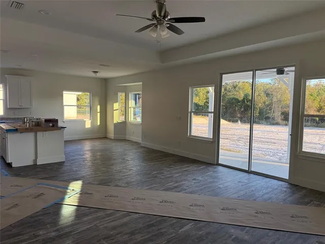 a view of an empty room with window and wooden floor