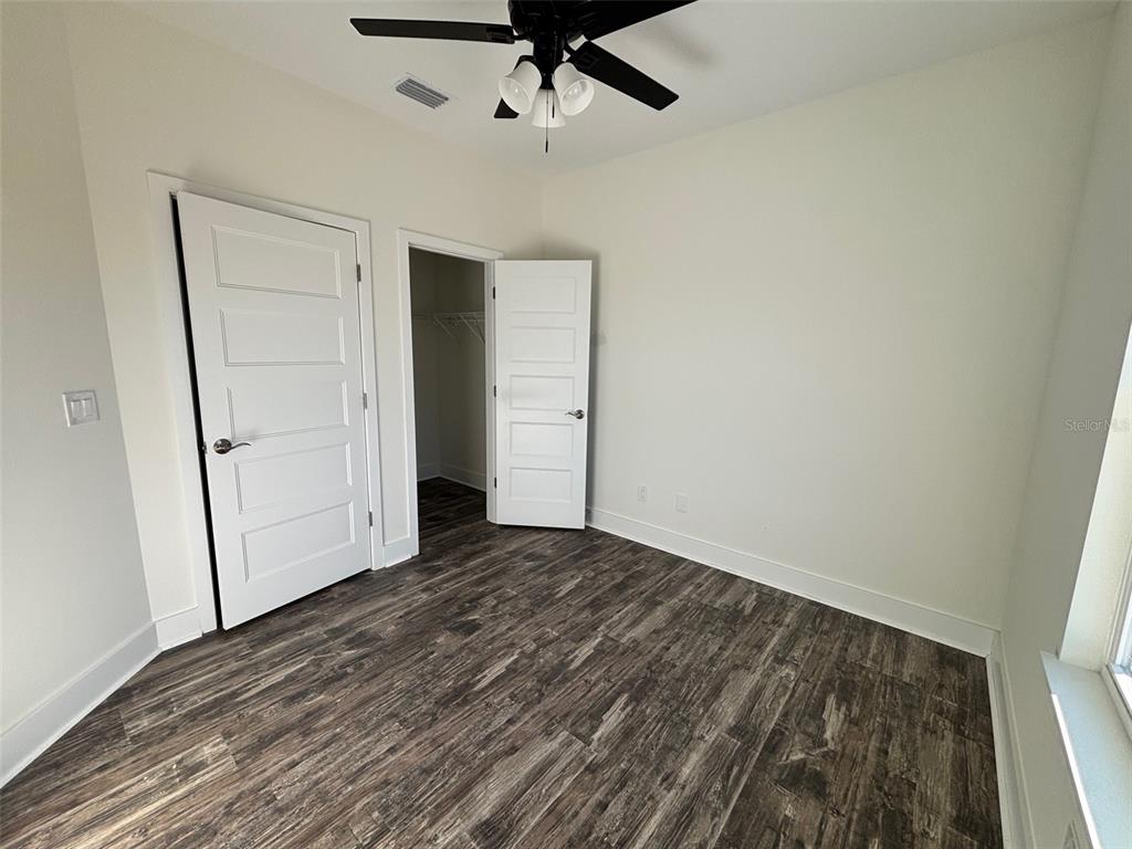 5949 South E County Road 21B Keystone Heights, FL 32656 - Photo 17 of 30 an empty room with wooden floor cabinet and a ceiling fan