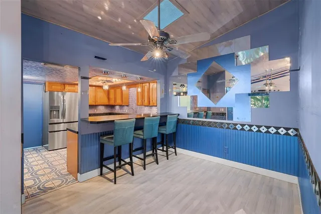 a kitchen with stainless steel appliances granite countertop a refrigerator a sink dishwasher a dining table and chairs with wooden floor