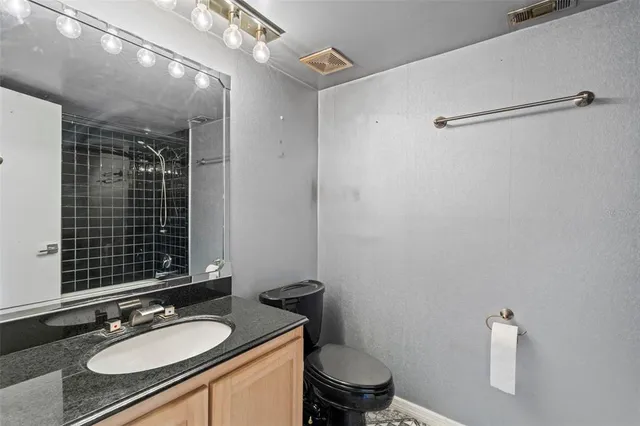 a bathroom with a granite countertop sink toilet a mirror and shower