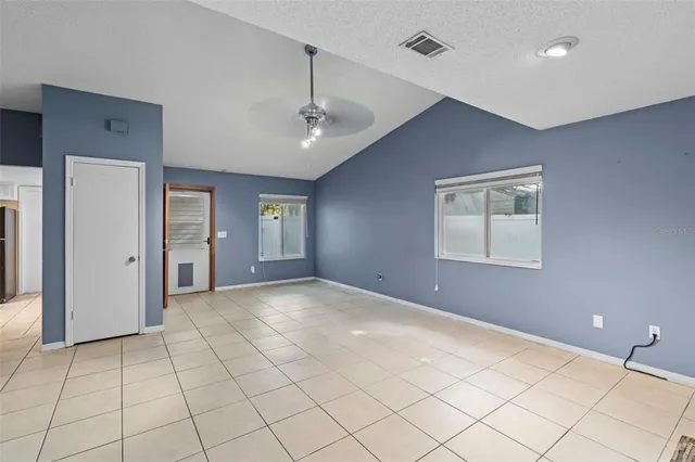 a view of an empty room with window and chandelier fan