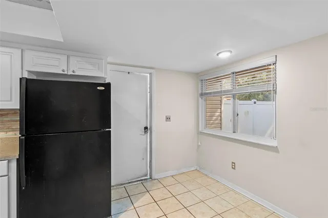 a view of a refrigerator in kitchen and white cabinets