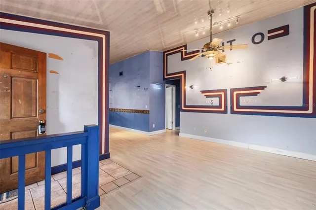 a view of a hallway with a dining table chairs wooden floor and a chandelier